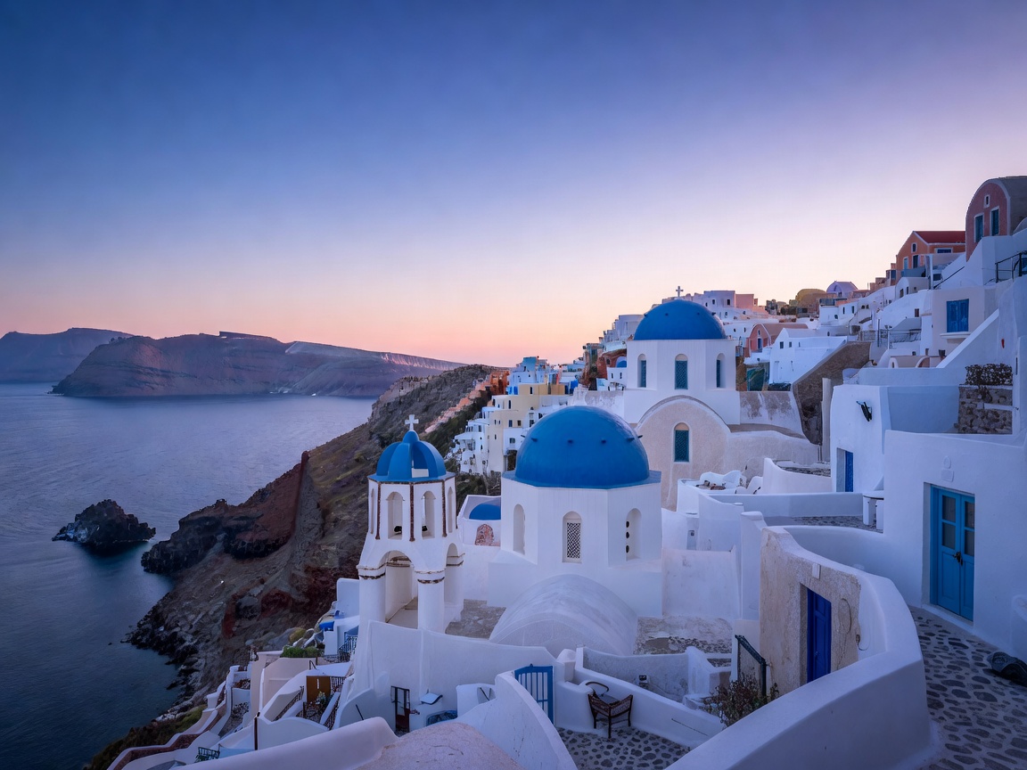 White buildings and blue domes of Oia Village in Santorini during twilight